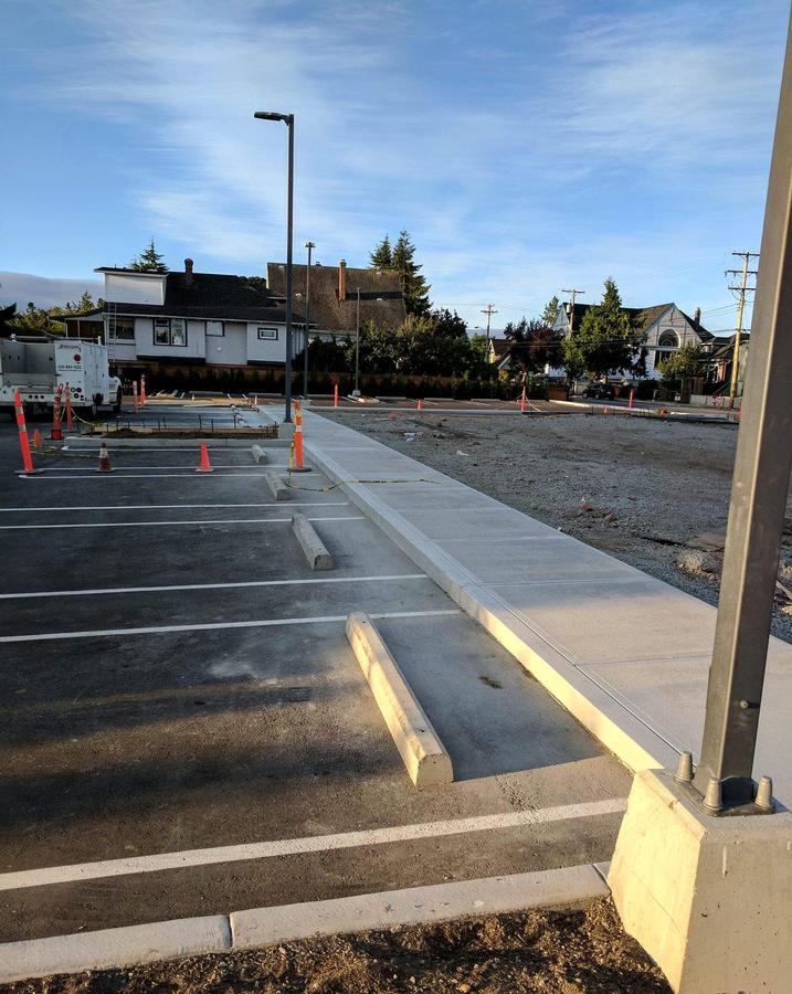 Finished concrete sidewalk and curb in evening light at a commercial parking lot in Esquimalt, BC