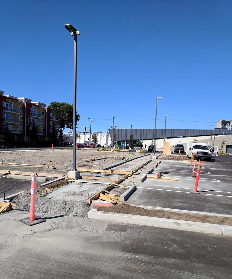 Formed curb line and compacted gravel base across a commercial lot in Esquimalt, BC