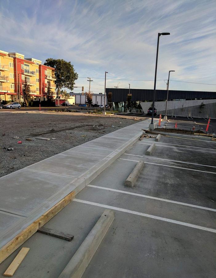 Finished concrete perimeter sidewalk, curbs and parking curb stops at a commercial lot in Esquimalt, BC