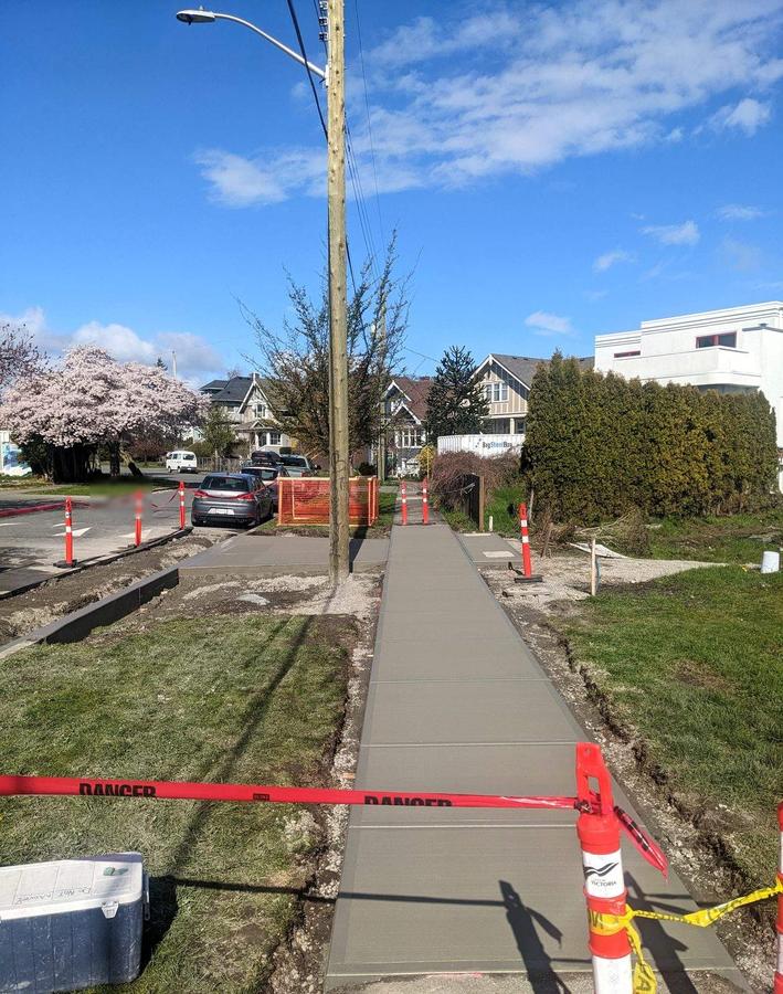 Freshly poured concrete curb and sidewalk run finished with tooled joints in Saanich, BC